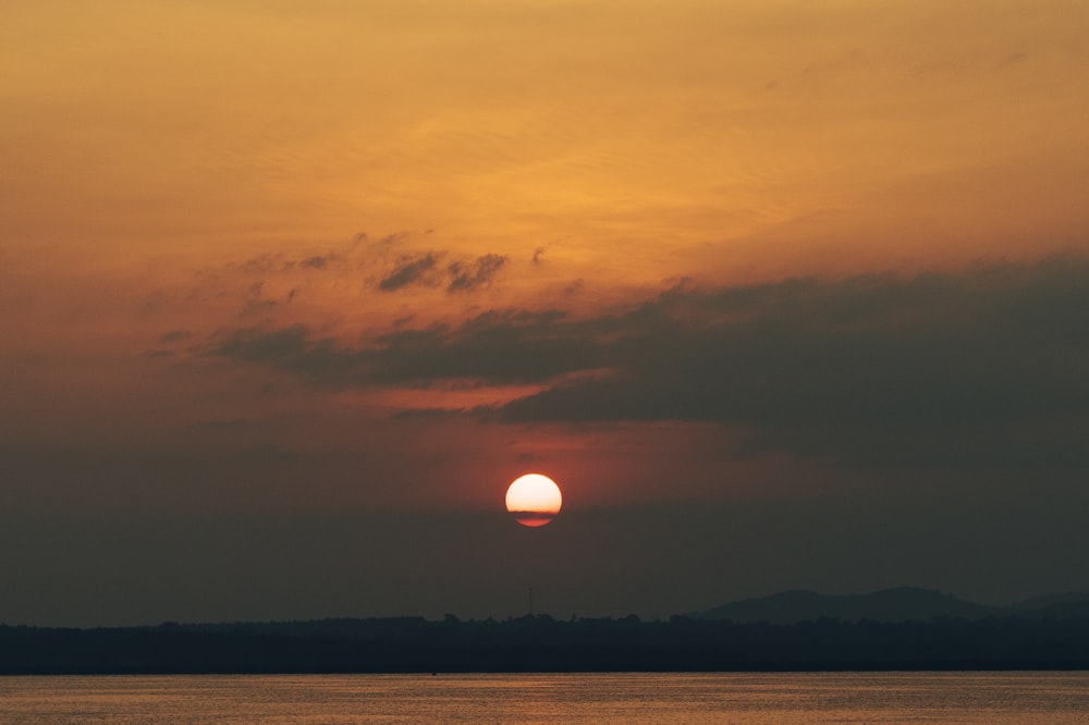 a large body of water with a sunset in the background