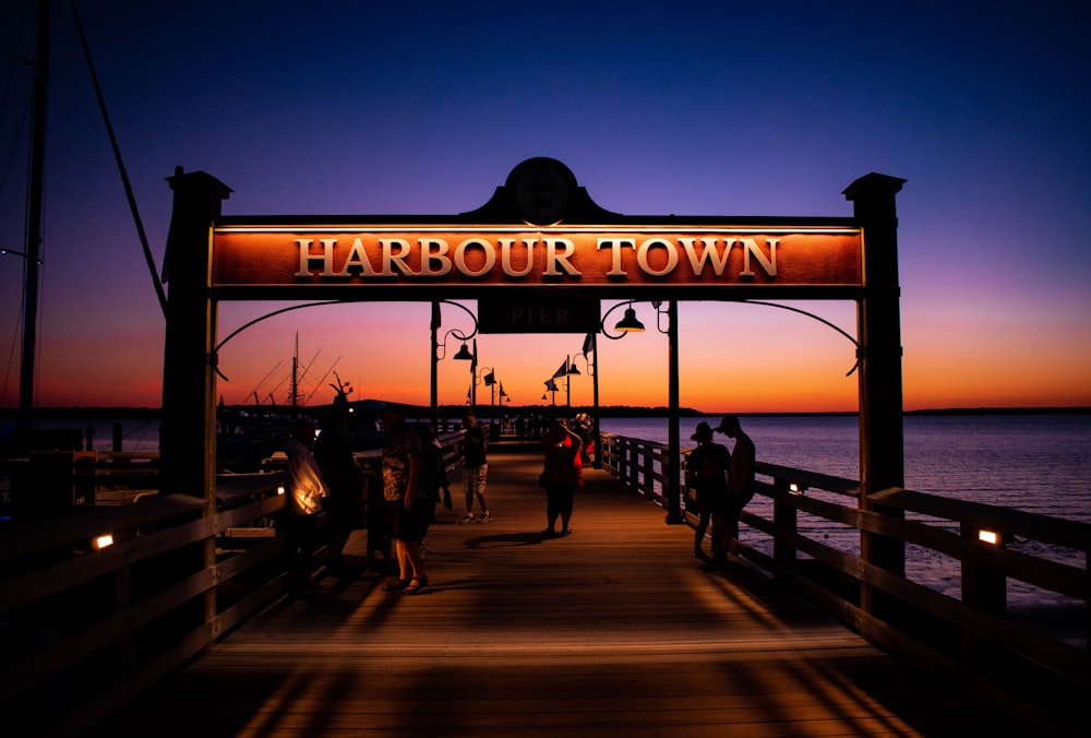 a group of people standing on a pier at sunset