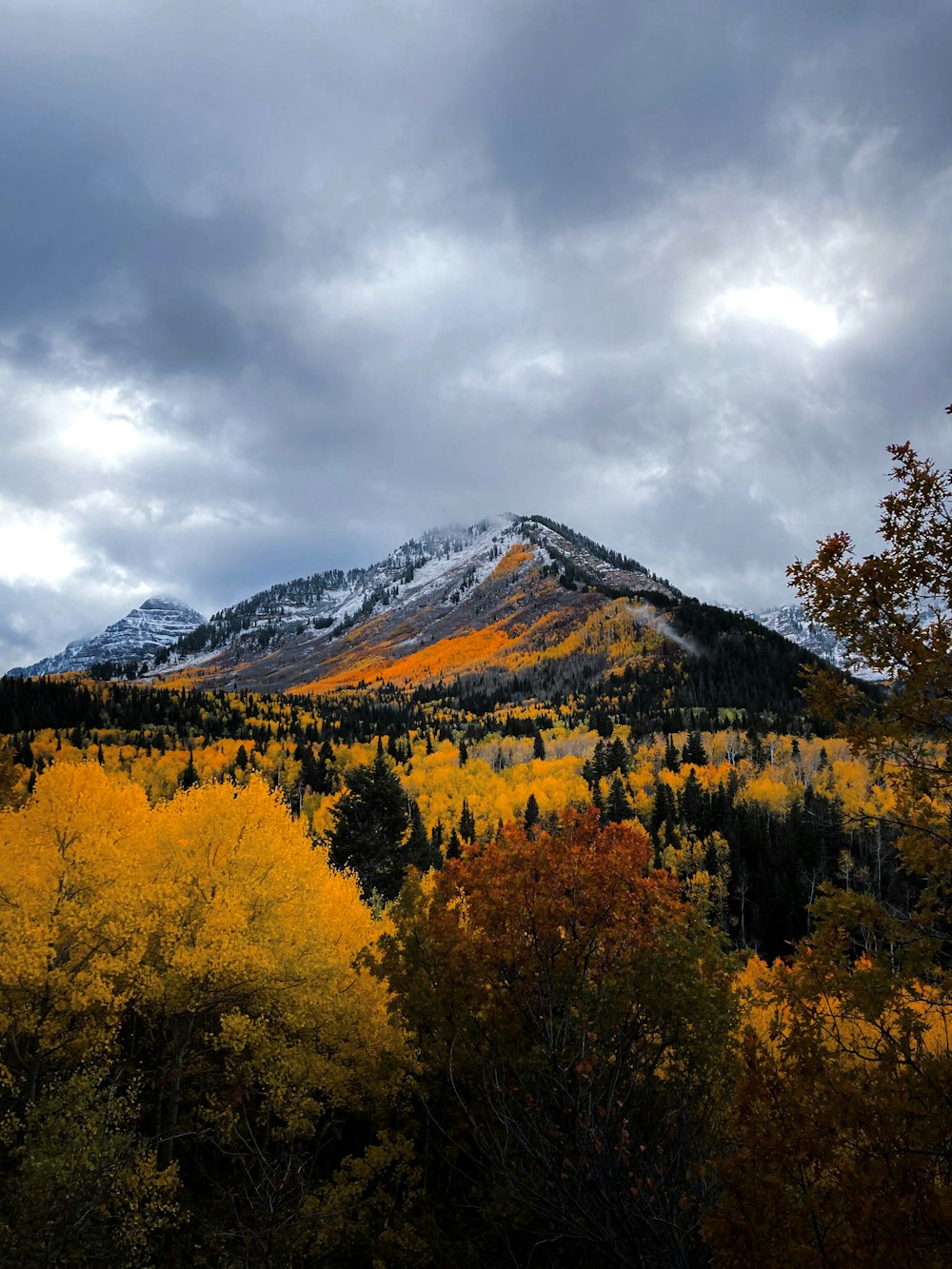 a mountain covered in snow covered mountains under a cloudy sky