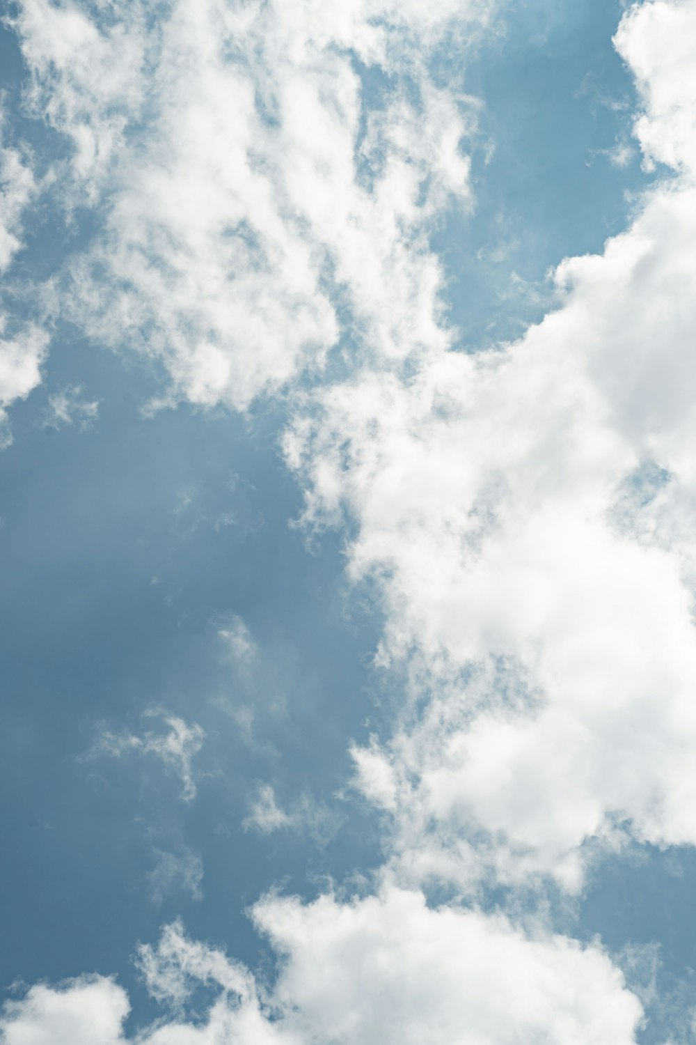 a plane flying through a cloudy blue sky