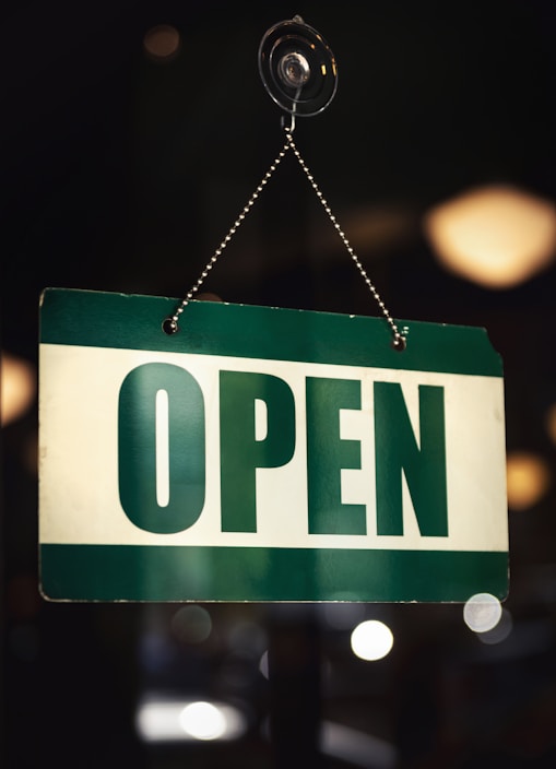 a green and white open sign hanging from a chain