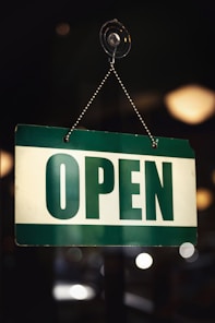 a green and white open sign hanging from a chain