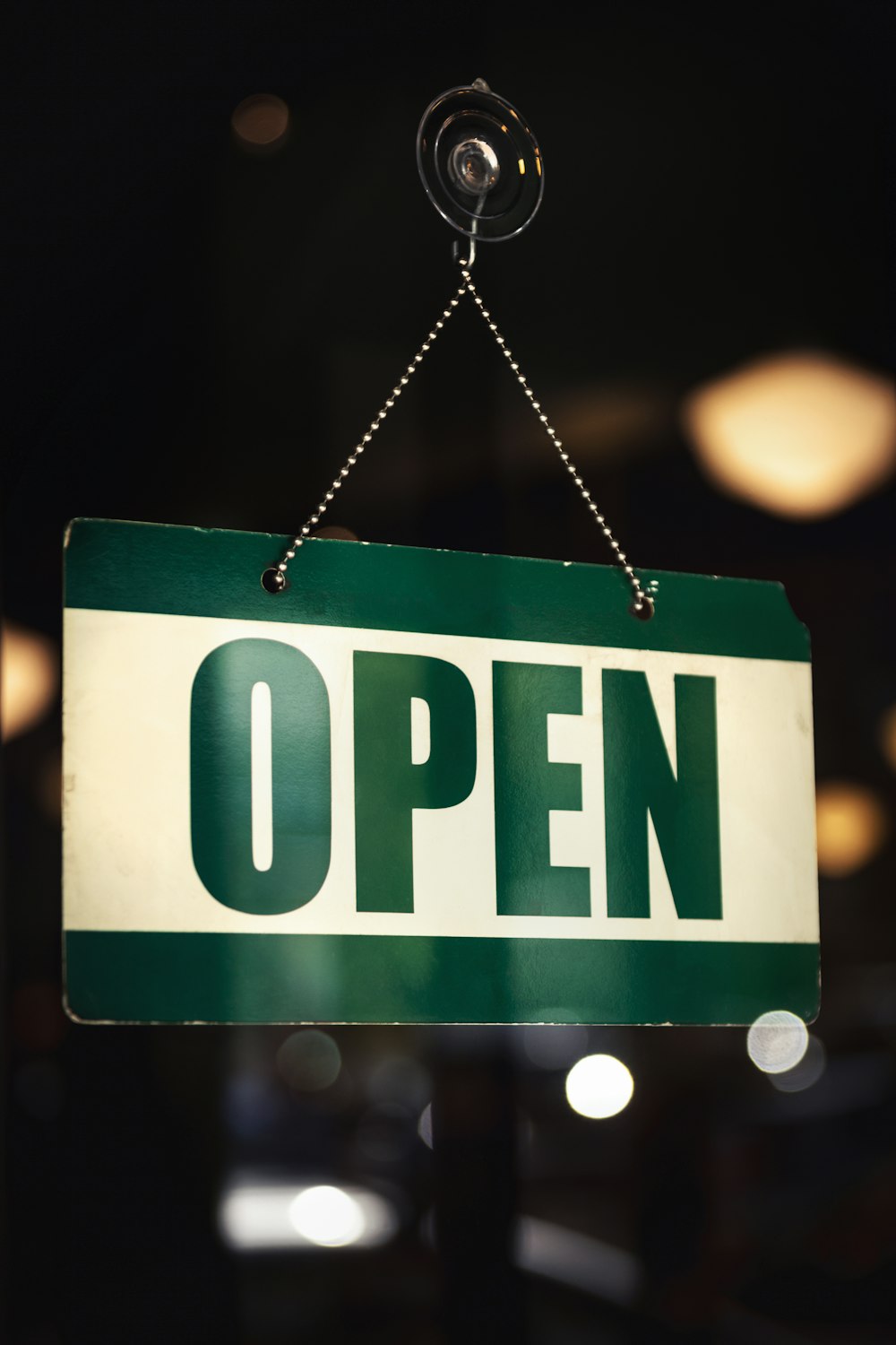 a green and white open sign hanging from a chain