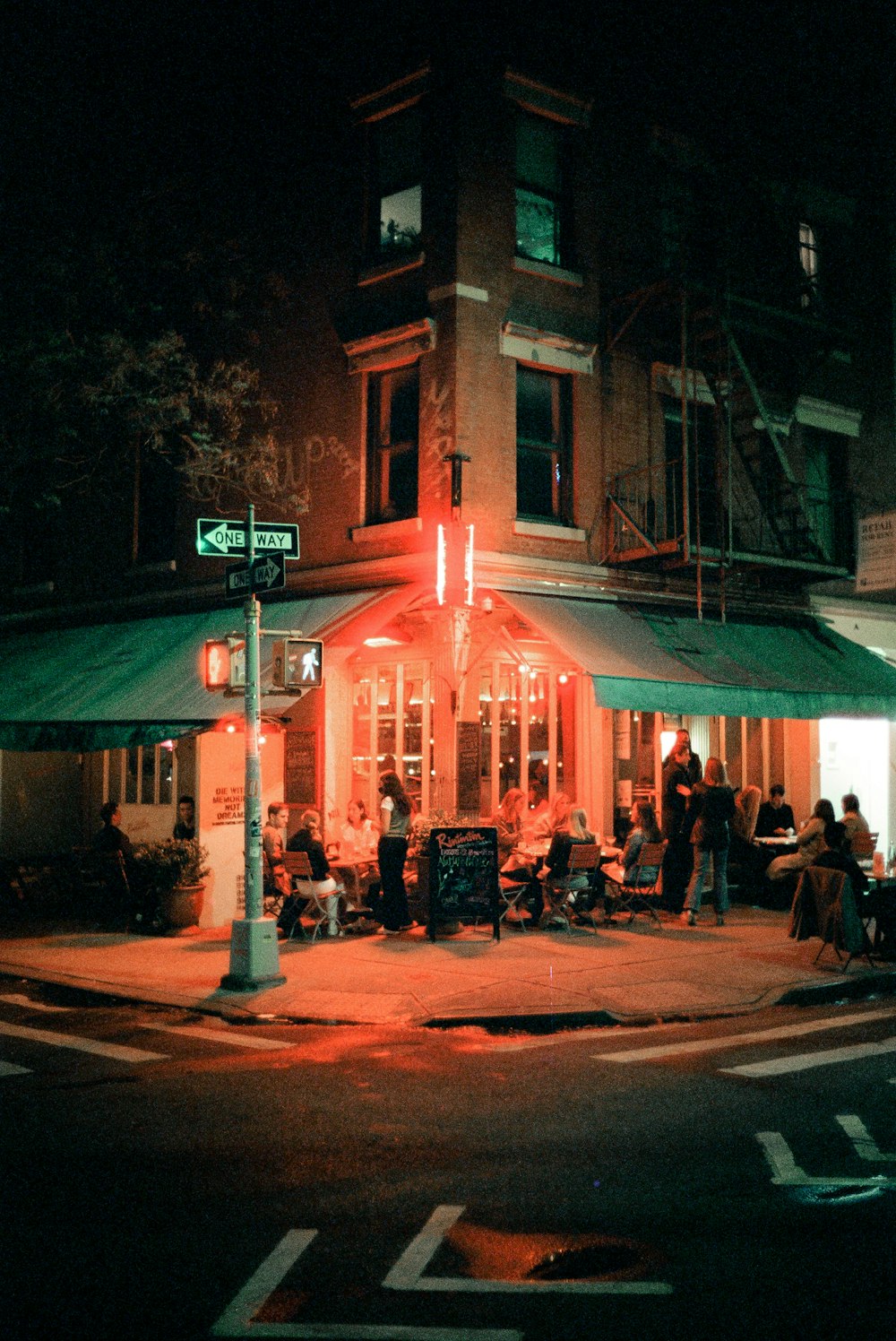 a group of people sitting outside of a restaurant at night