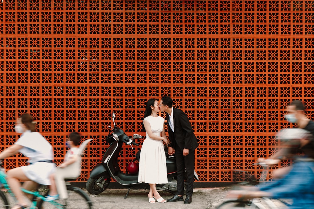 a man and a woman standing next to a scooter