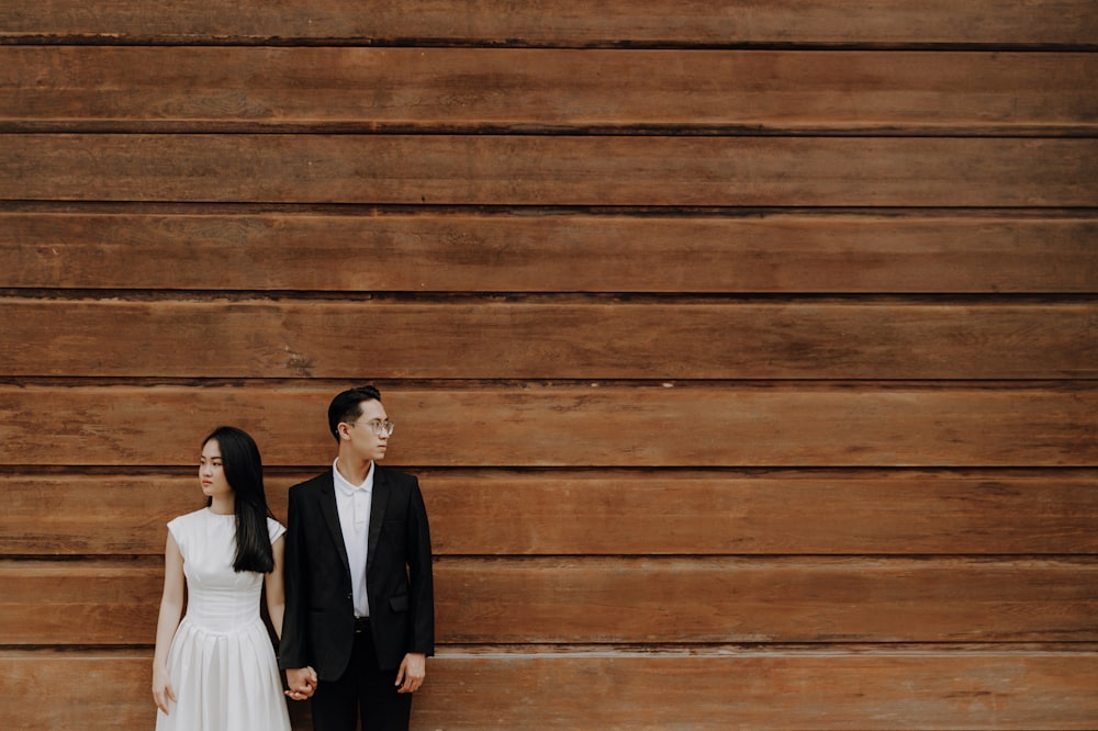 a man and a woman standing next to each other in front of a wooden wall