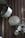Several metal pots and lids hang on a corrugated metal wall. The cookware is arranged on hooks, displaying various sizes and shapes. The larger pot is prominently positioned at an angle, while other smaller pots and lids are neatly lined up below.