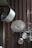 Several metal pots and lids hang on a corrugated metal wall. The cookware is arranged on hooks, displaying various sizes and shapes. The larger pot is prominently positioned at an angle, while other smaller pots and lids are neatly lined up below.