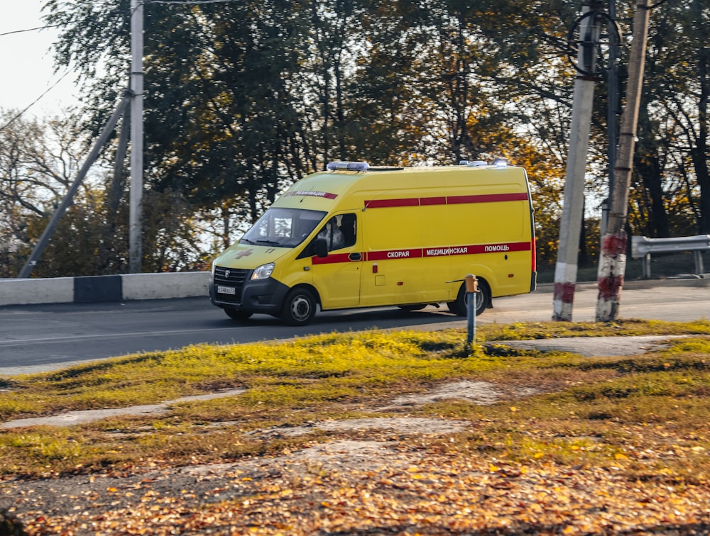 a yellow van driving down a street next to a forest