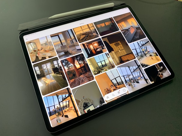 A tablet displaying a collection of interior design photos, showcasing rooms bathed in warm sunlight. The images feature modern, stylish living spaces with large windows, cozy seating, and decorative elements.