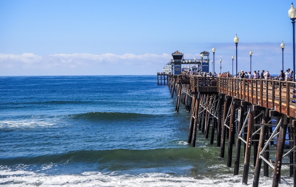 a pier with people standing on it next to the ocean