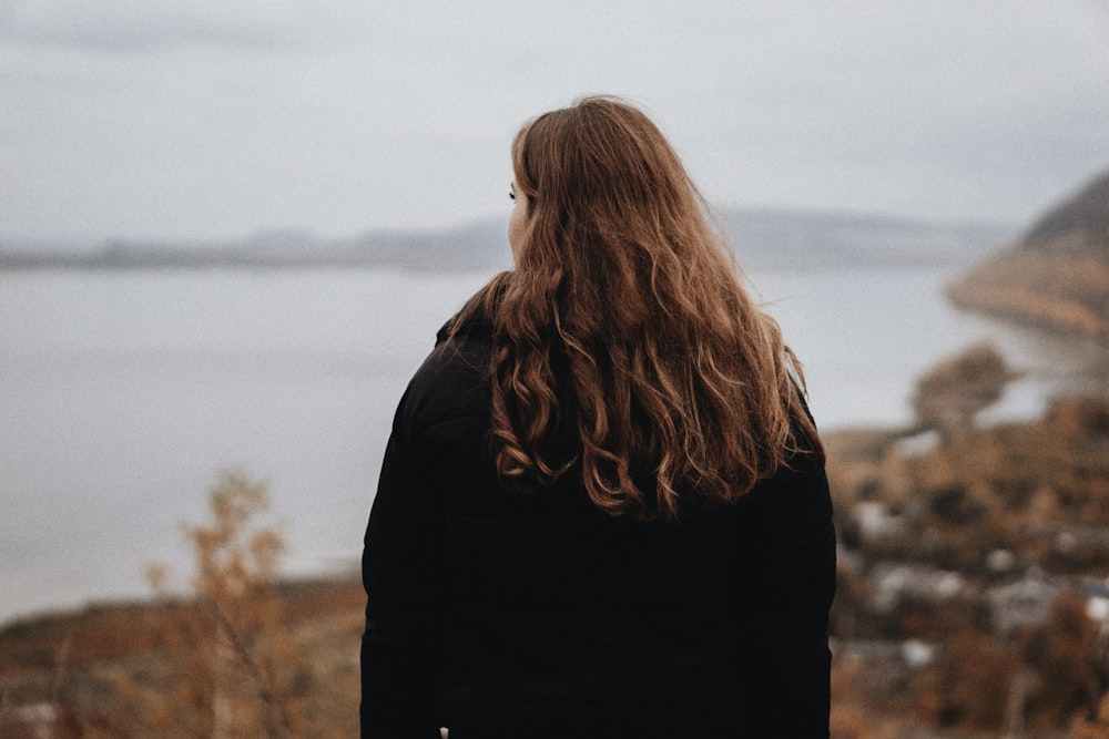 a woman standing on a hill looking at the water