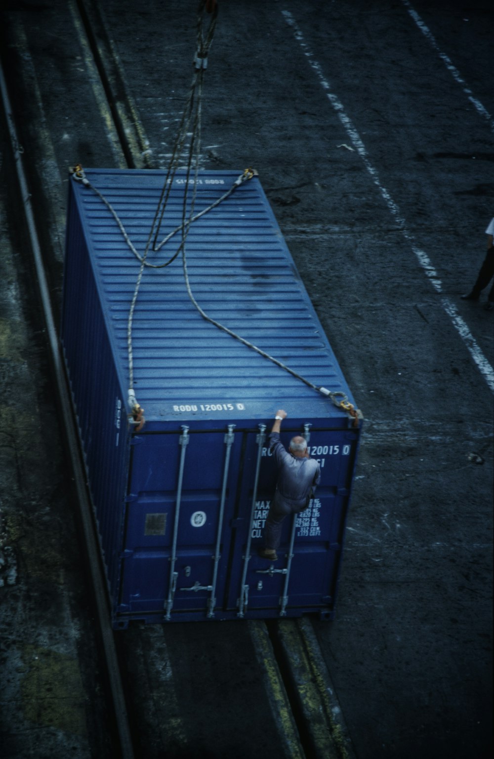 a man standing on top of a blue shipping container