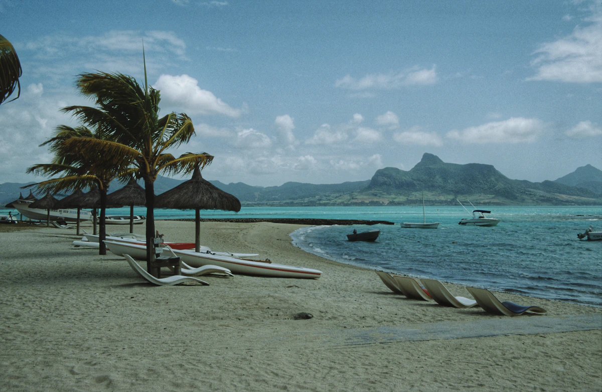 Palm-lined beach with boats moored in the turquoise lagoon on Mauritius' north coast
