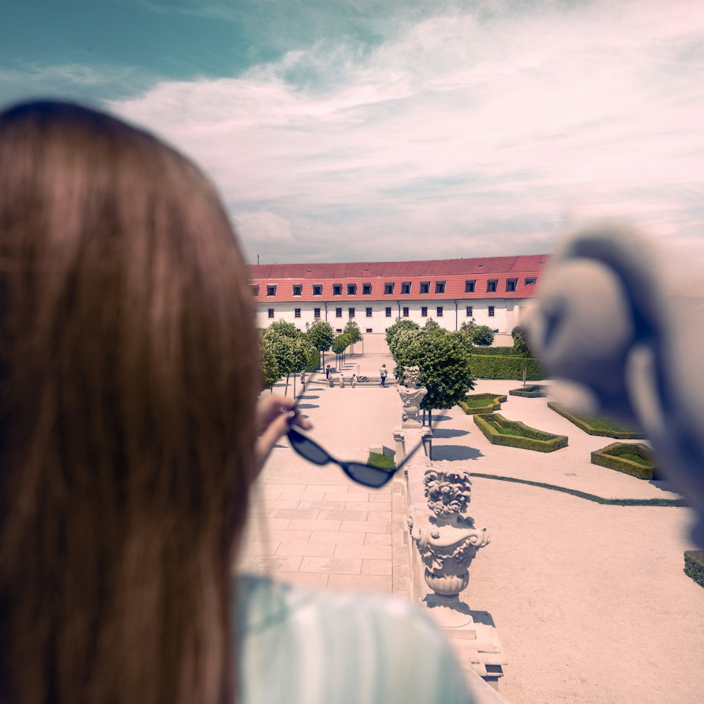 a woman holding a pair of sunglasses looking at a building