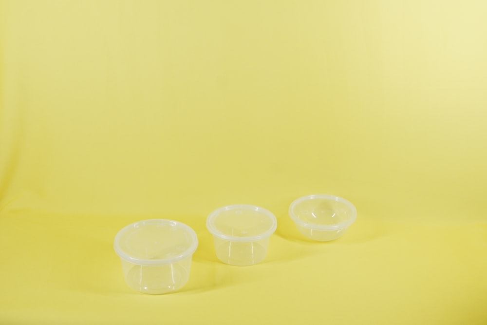 three plastic containers sitting on a yellow surface