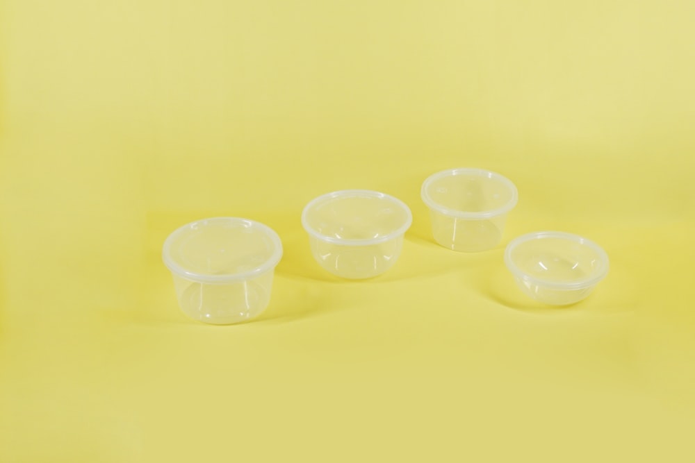 a group of three plastic containers sitting on top of a yellow surface