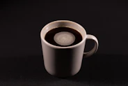 a white cup of coffee on a black table