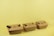 Three brown cardboard takeout boxes are neatly arranged in a row against a light yellow background. The boxes are closed with folded flaps on the top.