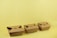 Three brown cardboard takeout boxes are neatly arranged in a row against a light yellow background. The boxes are closed with folded flaps on the top.