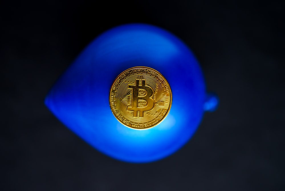 a bit coin sitting on top of a blue vase