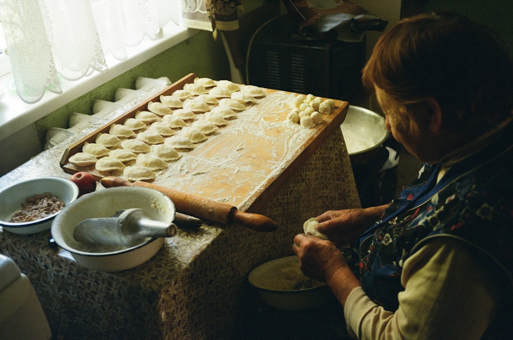 a woman in a kitchen making dough on a table