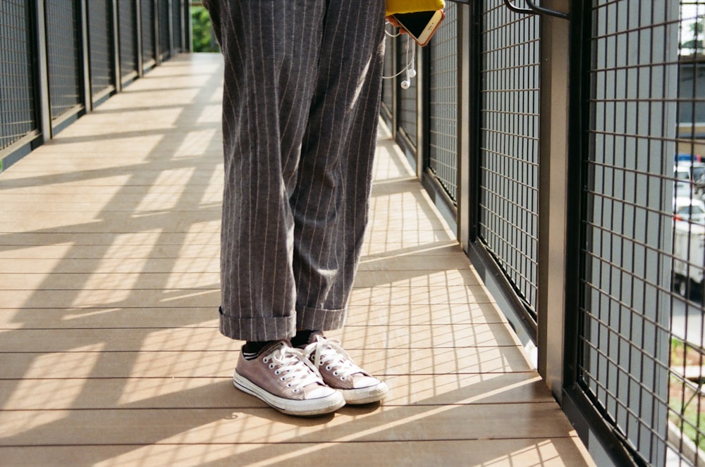 uma pessoa em pé em uma passarela segurando uma bolsa amarela