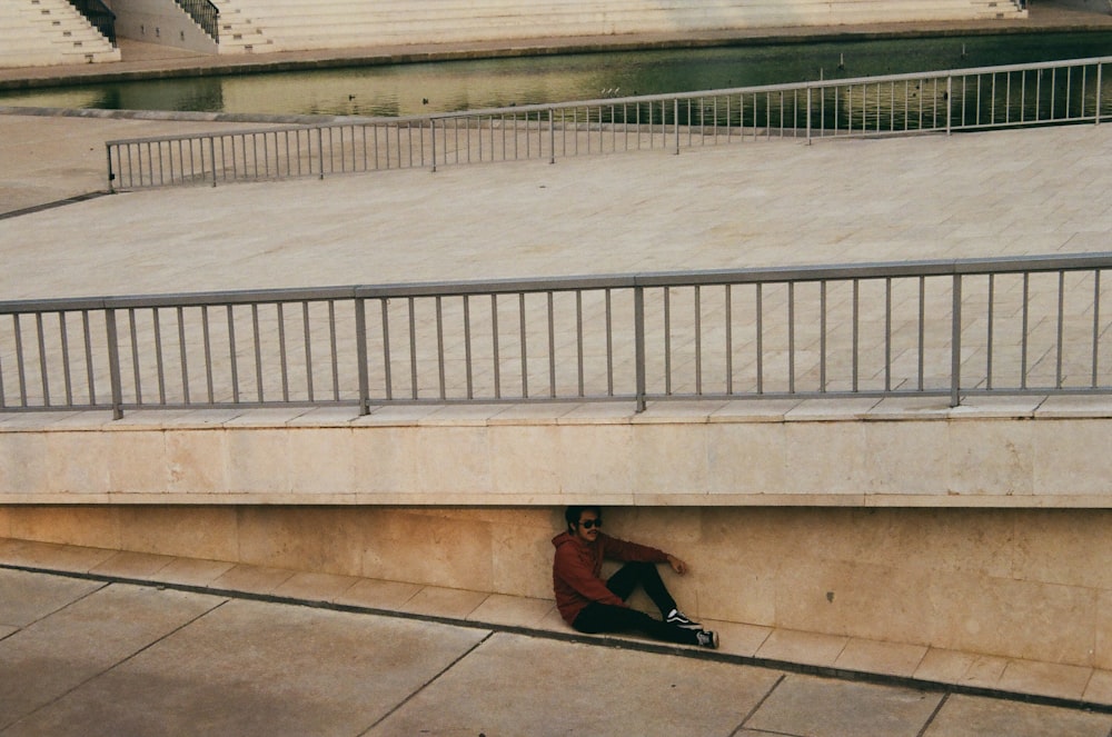 a person sitting on the ground under a bridge