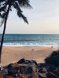 a couple of people standing on top of a sandy beach
