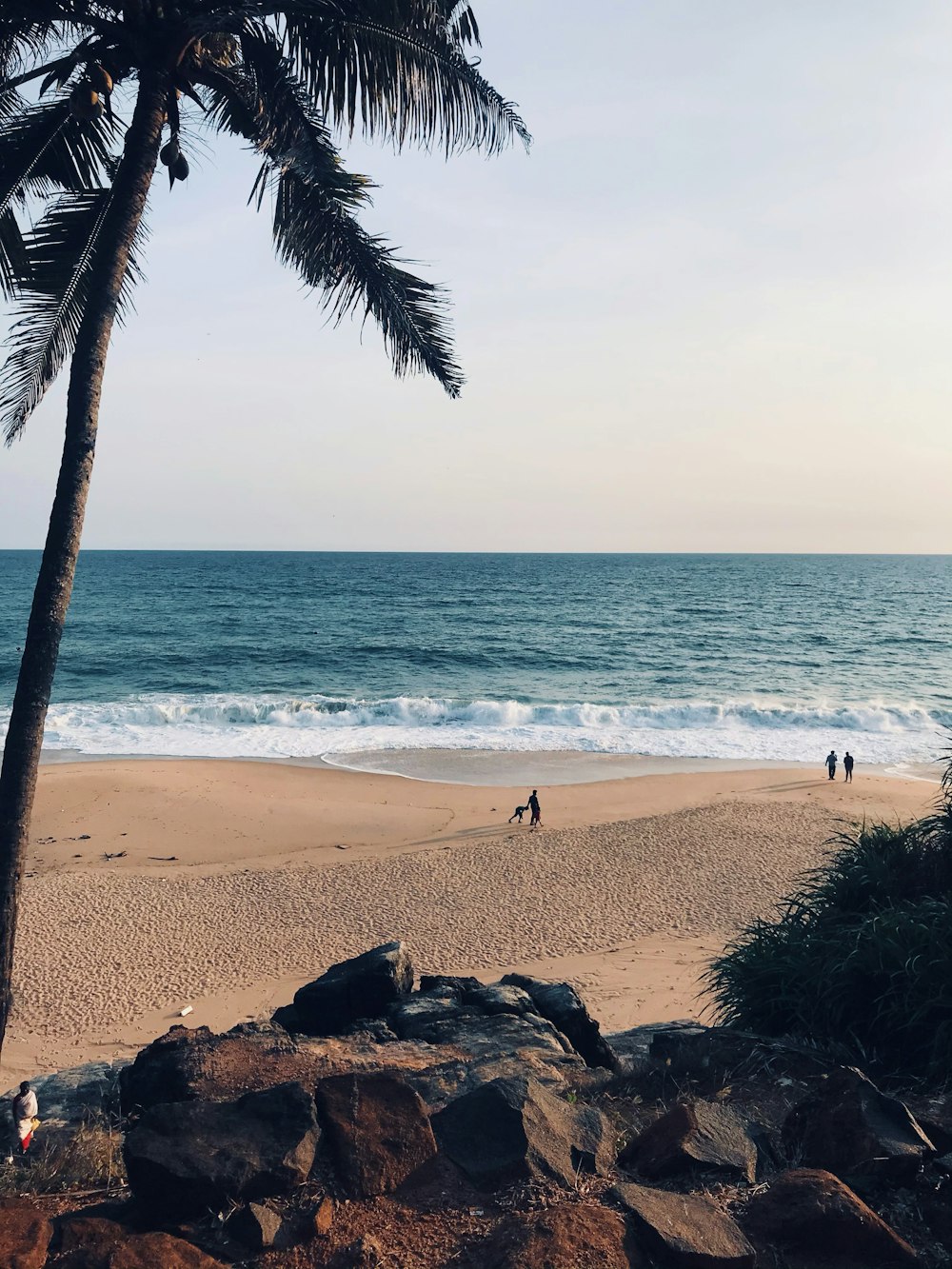 a couple of people standing on top of a sandy beach