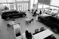 A friendly car dealership team assisting a client with paperwork in a bright, modern showroom.