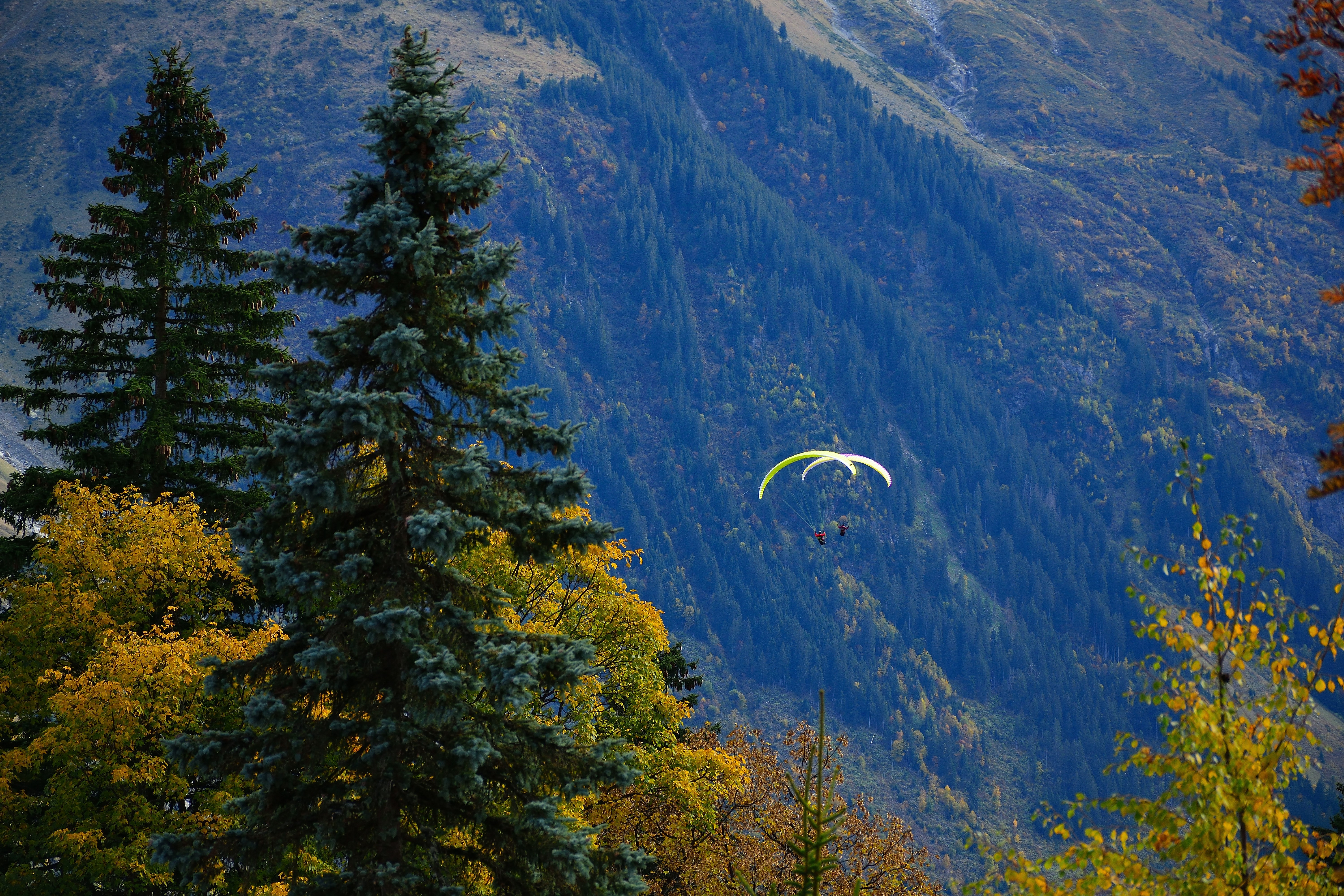two paragliders are flying over a mountain range