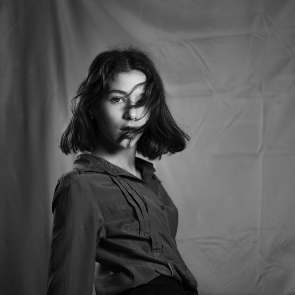 a black and white photo of a woman with her hair blowing in the wind