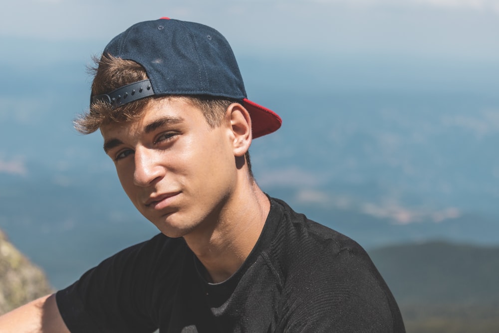 a young man wearing a baseball cap and a black shirt