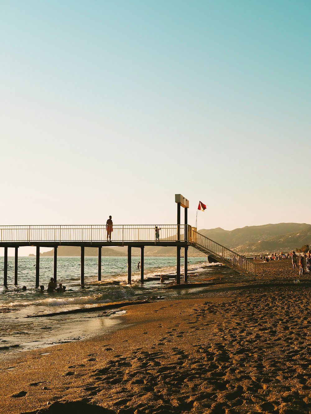 people are standing on a pier at the beach