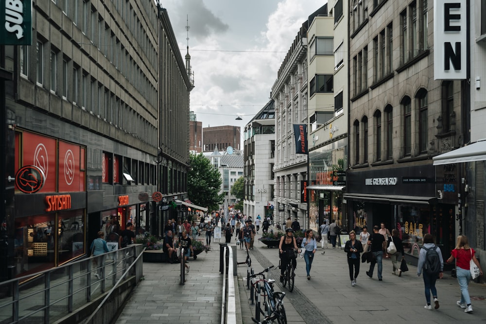 a group of people walking down a street next to tall buildings