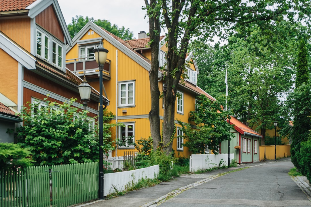 a yellow house with a red roof and a green fence,