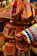 A close-up of a vibrant, handcrafted handbag with rainbow hues displayed on a wooden table.