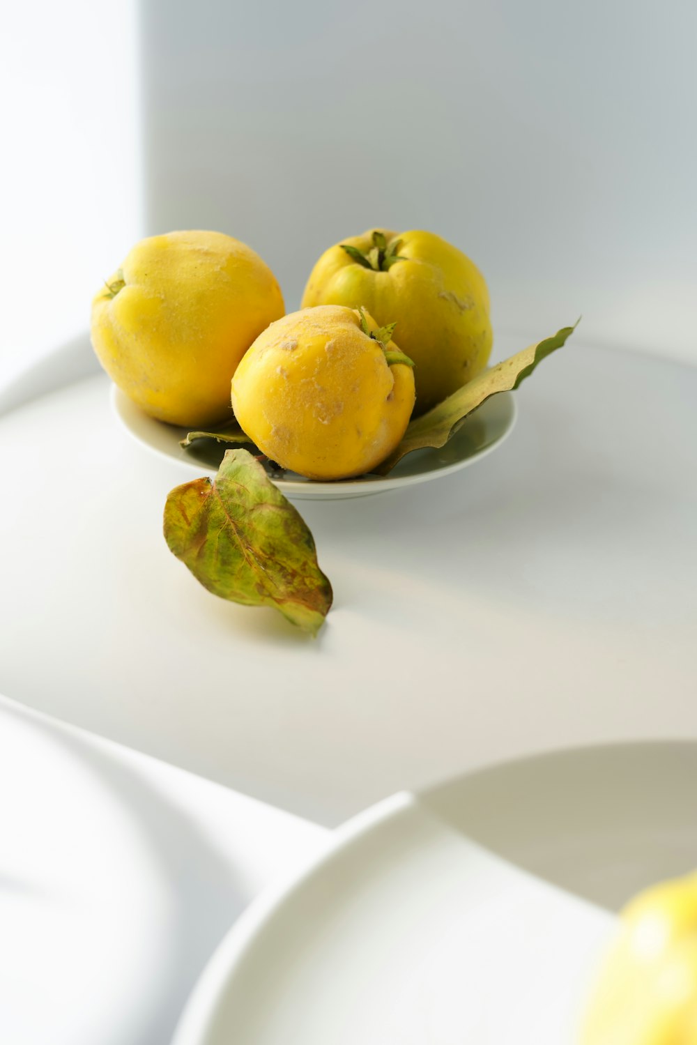 a white plate topped with three lemons and a green leaf