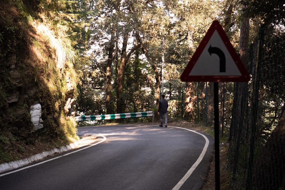 a man walking down a road next to a forest