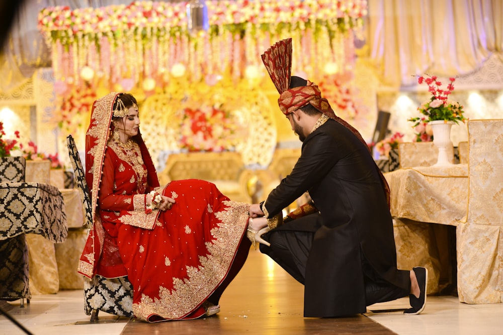 a man kneeling down next to a woman in a red dress