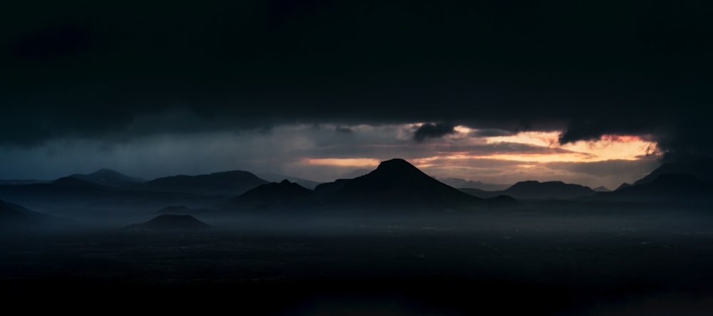 Un cielo oscuro con nubes y montañas al fondo