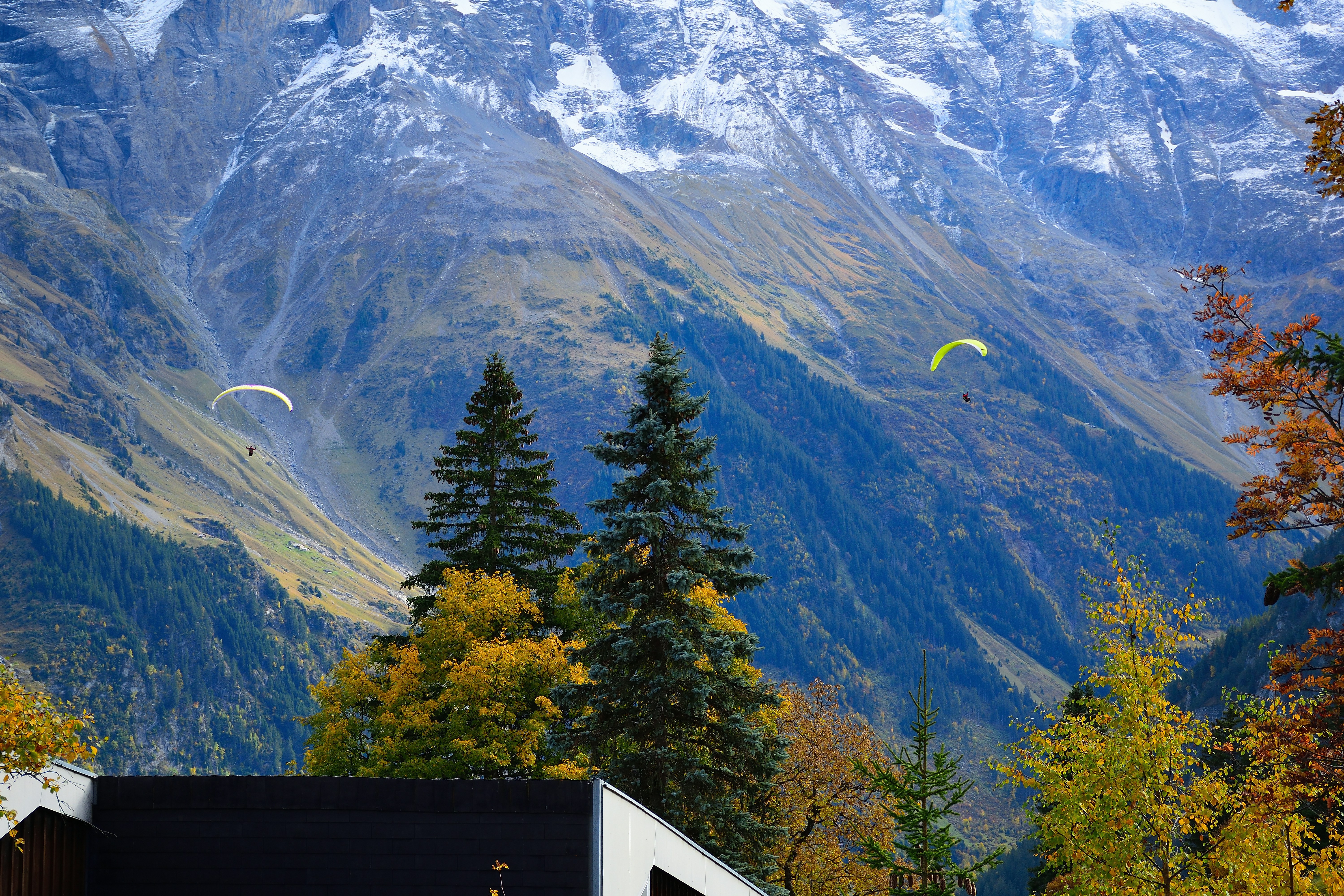 two paragliders are flying over a mountain range, 
