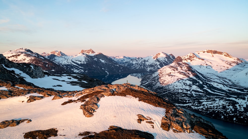 a snow covered mountain range with a lake in the foreground