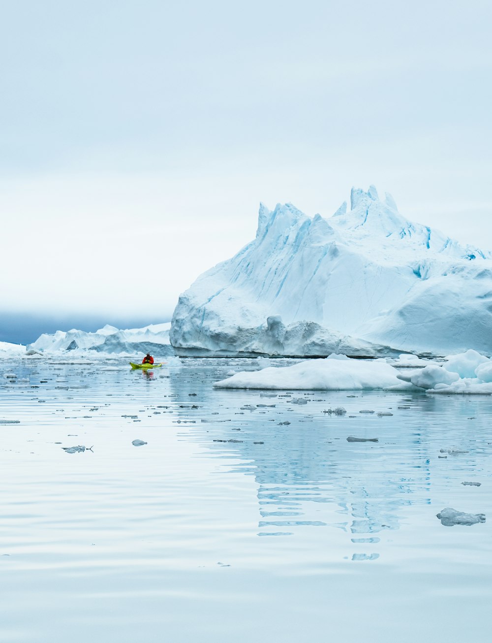 an iceberg with a kayak in the water