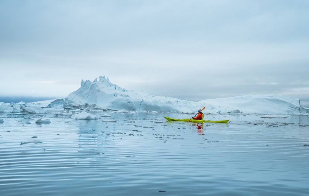 a person in a kayak in front of icebergs