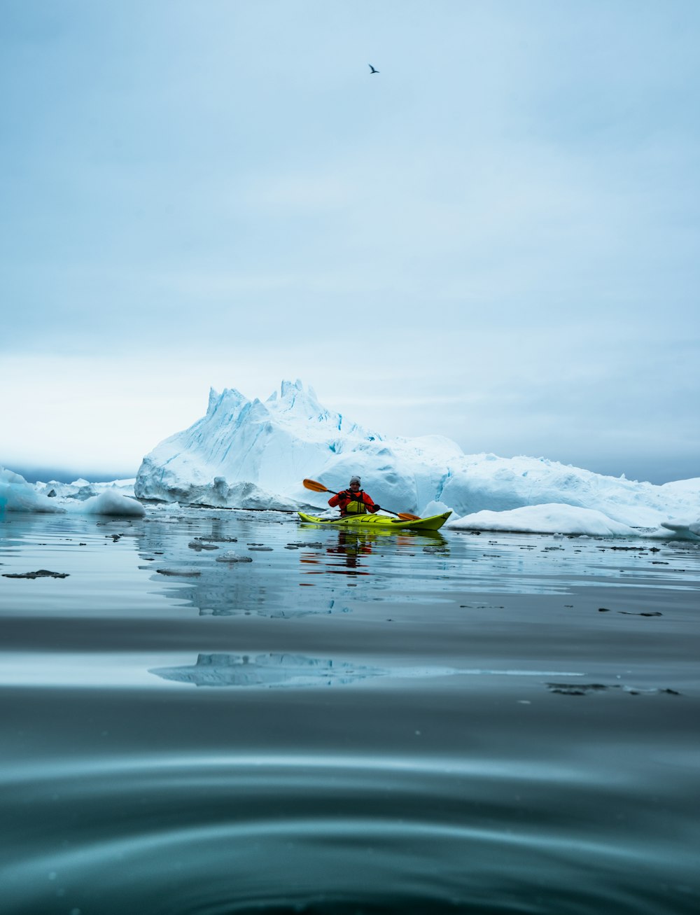 a person in a kayak in front of icebergs