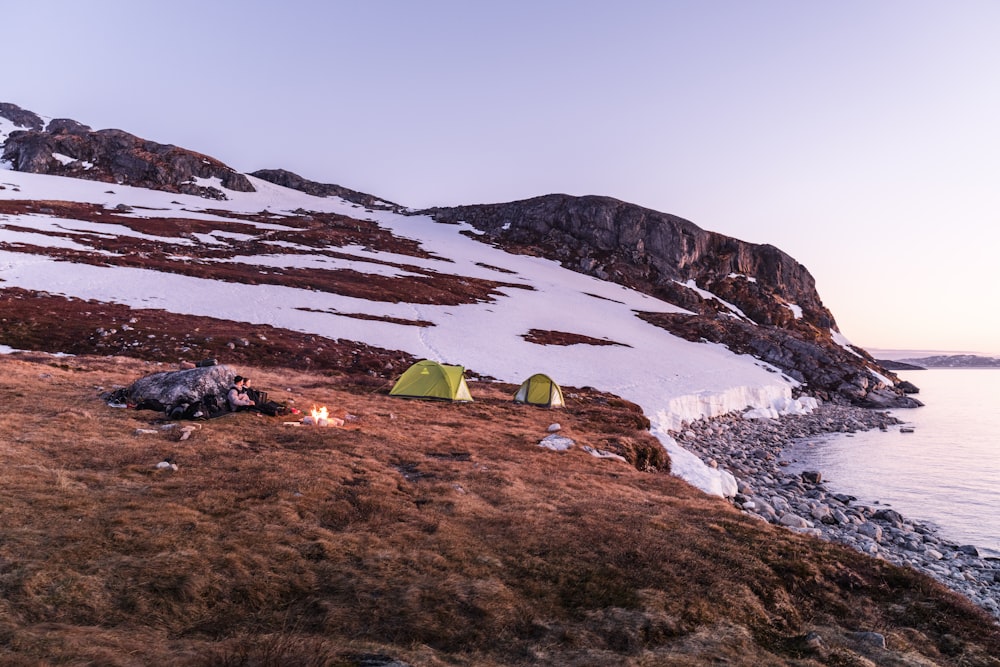 a couple of tents sitting on top of a snow covered hillside