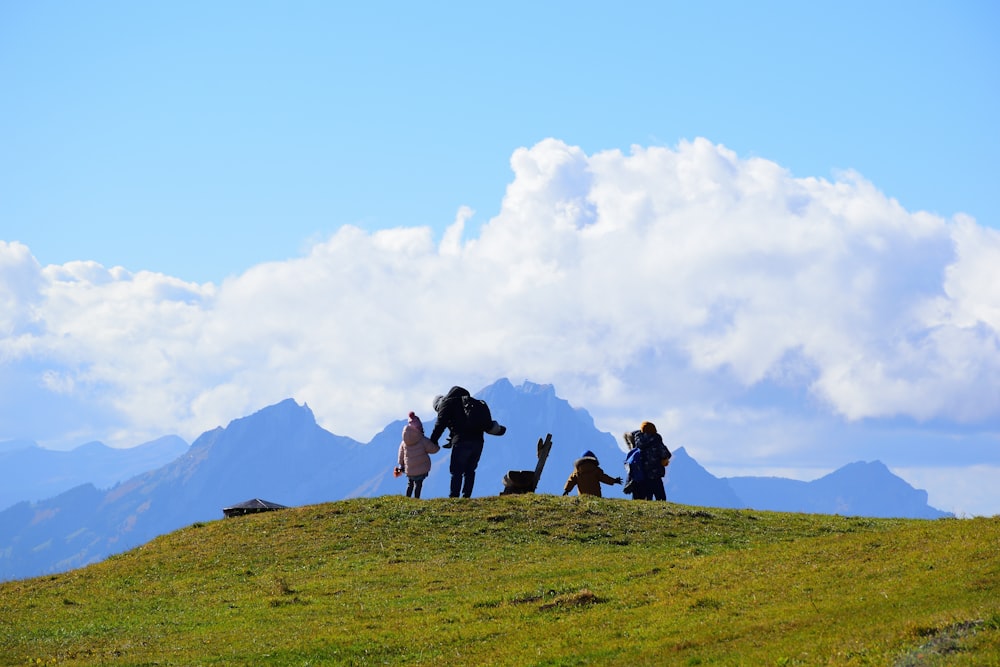 a group of people standing on top of a lush green hillside