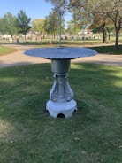 A sturdy concrete birdbath with intricate leaf designs.